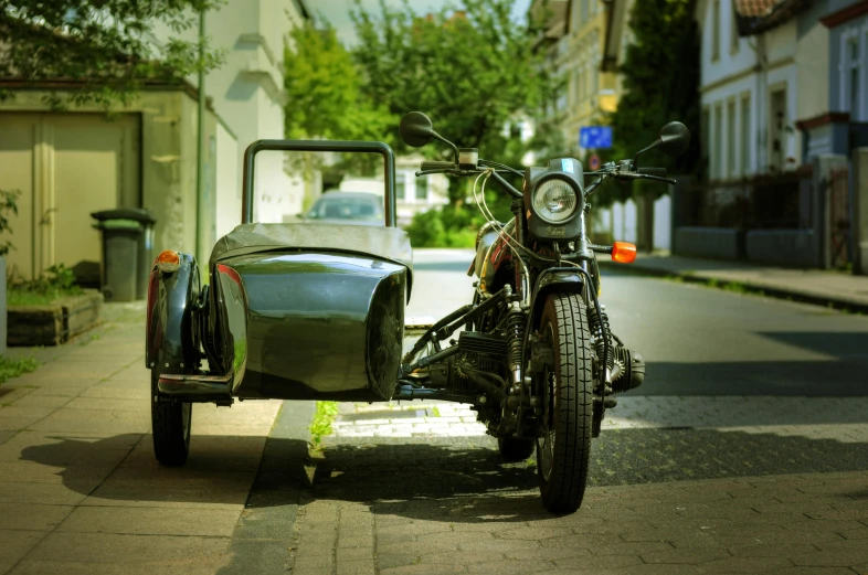 a motorcycle parked on the side of a street next to a car, an album cover, by Adam Marczyński, unsplash, square, steampunk car, set in ww2 germany, a green
