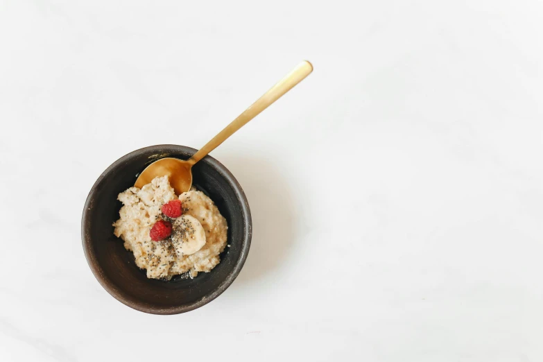 a bowl of oatmeal with a spoon in it, by Pablo Rey, trending on unsplash, cutout, gold, petite, grey
