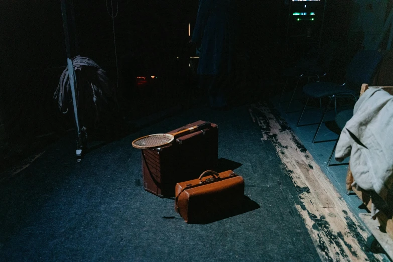 a couple of suitcases sitting on top of a carpet, an album cover, unsplash, theatre stage, standing in a dimly lit room, rinko kawauchi, miscellaneous objects