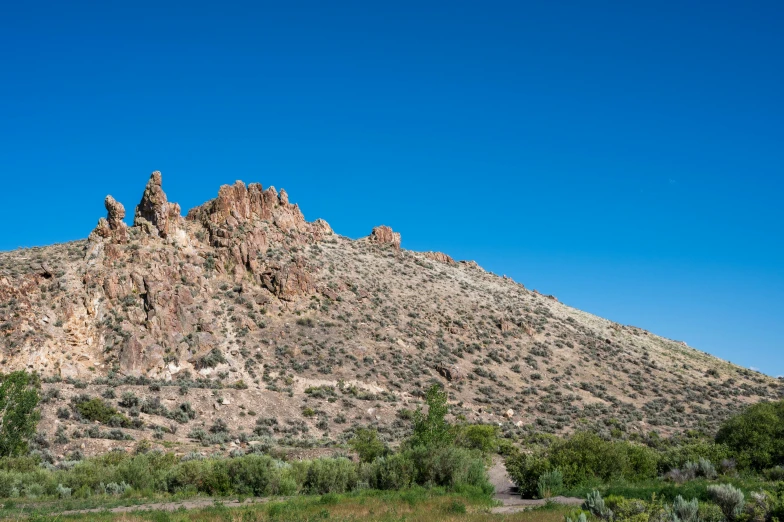 a mountain that is in the middle of a field, by Arnie Swekel, unsplash, hillside desert pavilion, tall stone spires, oregon trail, background image