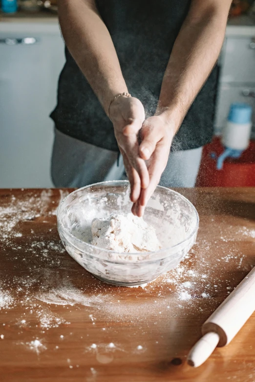 a person kneads dough in a bowl on a table, a portrait, trending on pexels, made of glazed, focus on full - body, pastel', cooking