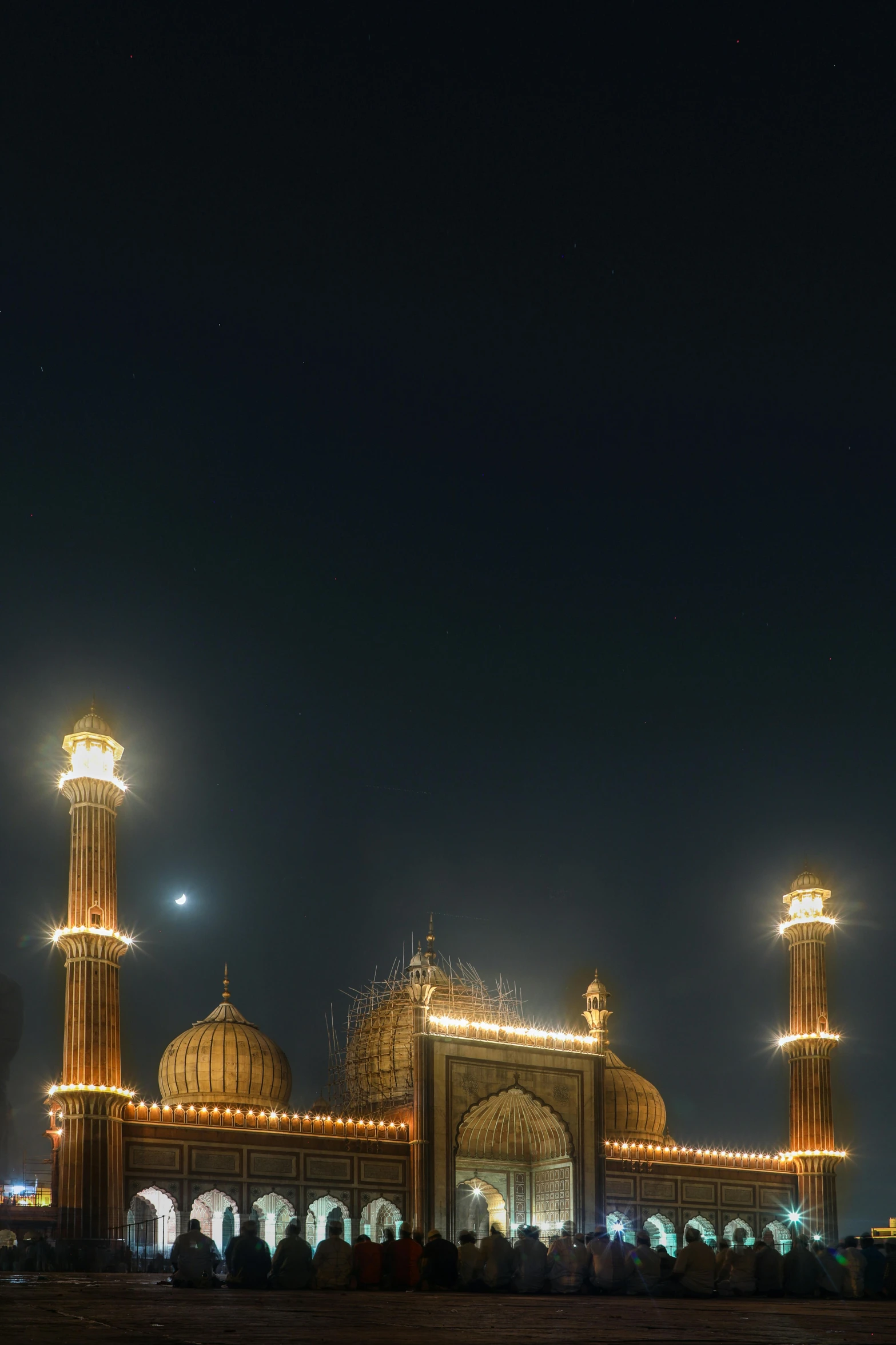 a group of people standing in front of a building at night, by Sudip Roy, renaissance, minarets, high detail photo, two moons lighting, high-resolution photo