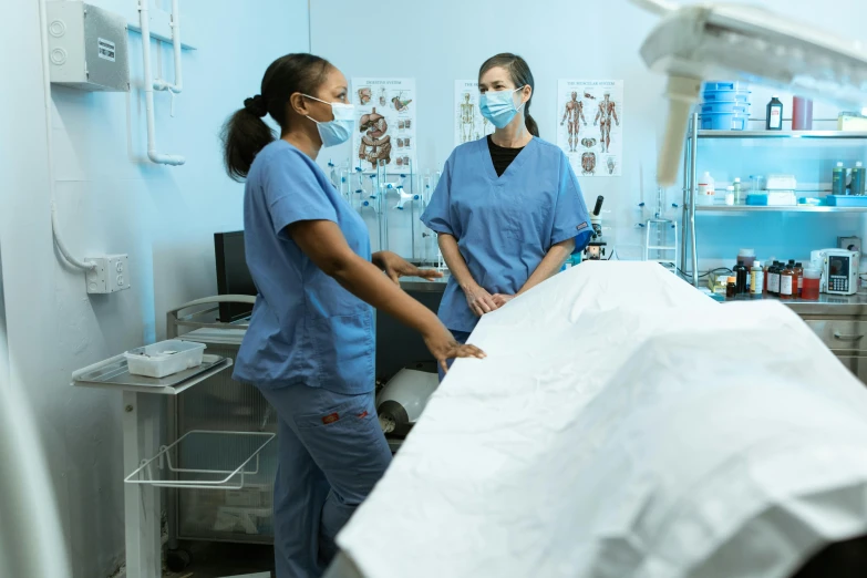a couple of women standing next to each other in a room, operating room, profile image, thumbnail, surgical gown and scrubs on
