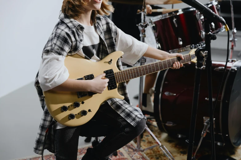 a woman playing a guitar in a recording studio, trending on pexels, photorealism, finn wolfhard, holding electric guitar, high quality photo, student