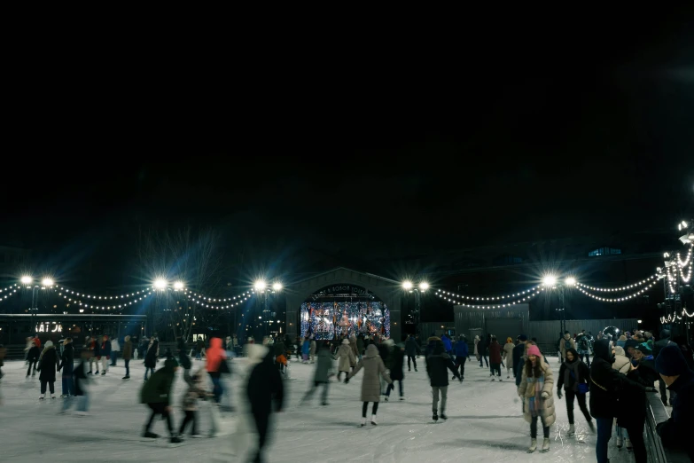 a group of people riding skis on top of a snow covered slope, the river is full of lights, sportspalast amphitheatre, walking on ice, northern star at night