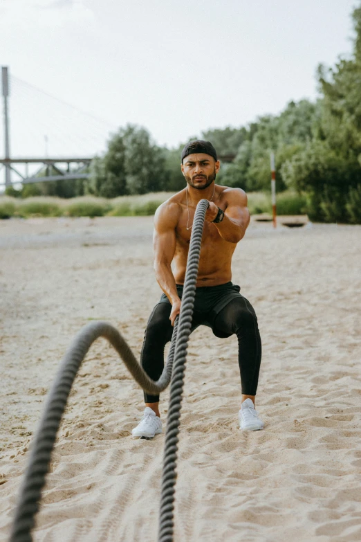 a man doing battle ropes on the beach, by Adam Marczyński, pexels contest winner, mid-shot of a hunky, riyahd cassiem, tubing, 🚿🗝📝