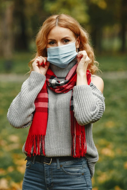 a woman wearing a face mask in a park, a portrait, by Adam Marczyński, shutterstock, fine art, red sweater and gray pants, scarf, a blond, square