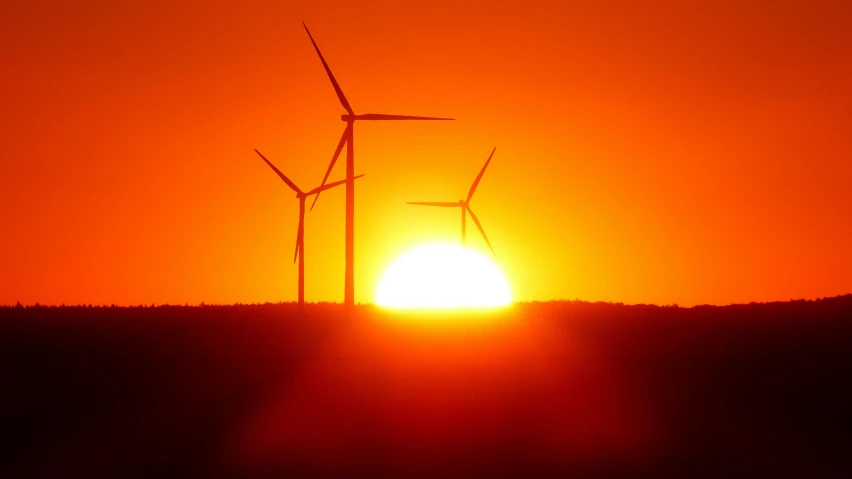 the sun is setting behind two wind turbines, a picture, by Joseph Werner, fan favorite, orange sun set, zoomed out shot, shot in canon