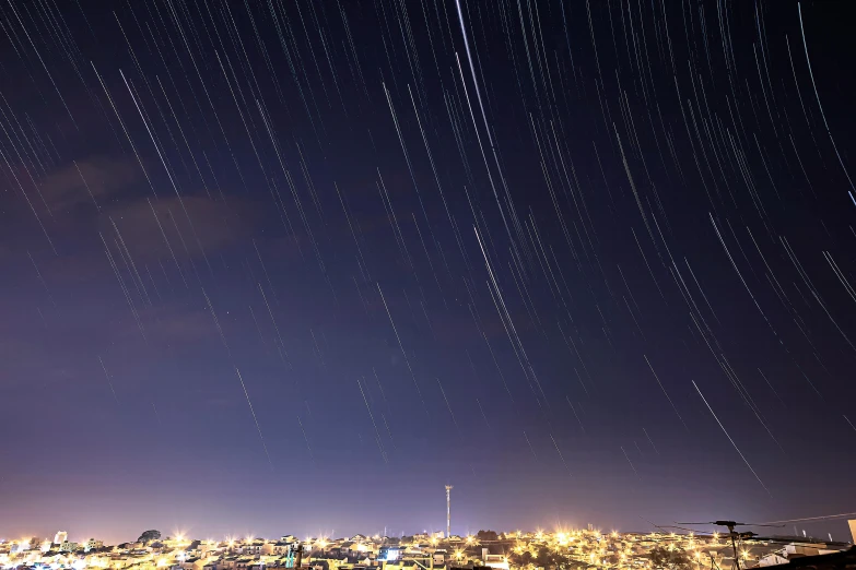 a view of a city at night from the top of a hill, by Dan Scott, unsplash contest winner, hurufiyya, star trails above, star rain, reykjavik, many stars in the night sky