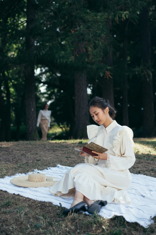 a woman sitting on a blanket reading a book, inspired by Shin Saimdang, renaissance, forest picnic, white suit and hat, in karuizawa, wearing a linen shirt