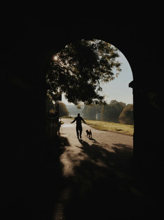 a person walking a dog through a tunnel, by Sebastian Spreng, dappled afternoon sunlight, walking out of a the havens gate, unsplash photography, multiple stories