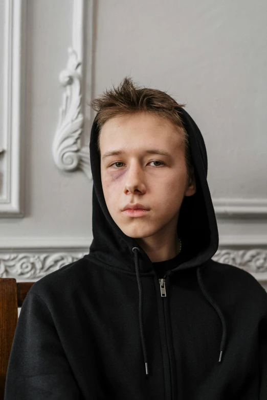 a young man sitting on top of a wooden bench, by Julia Pishtar, trending on pexels, hyperrealism, bruised face, in a black hoodie, portrait of 1 5 - year - old boy, ilya golitsyn