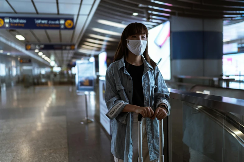 a woman wearing a face mask and holding a suitcase, a picture, shot on sony a 7, rectangle, black. airports, iu