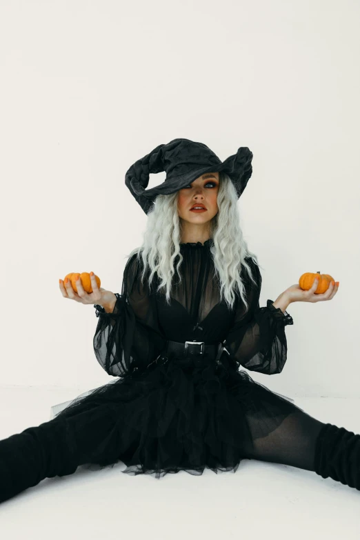 a woman in a witch costume sitting on the floor, trending on pexels, with curly black and silver hair, black hat, amy sol in the style of, cl