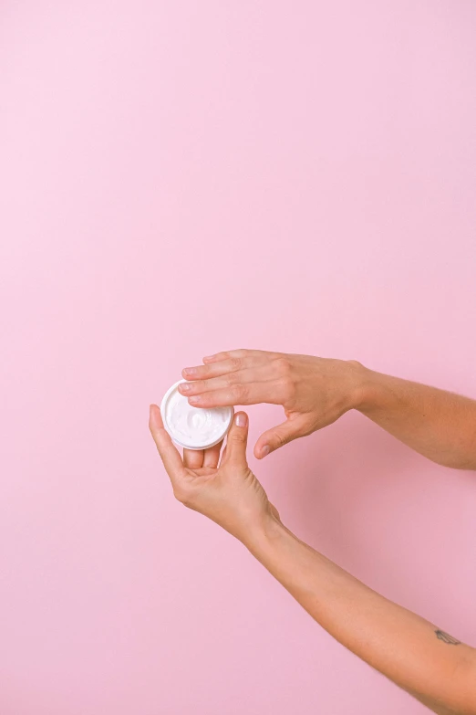 a woman holding a jar of cream on a pink background, a picture, by Olivia Peguero, trending on pexels, made of lab tissue, circle, back - shot, high angle view