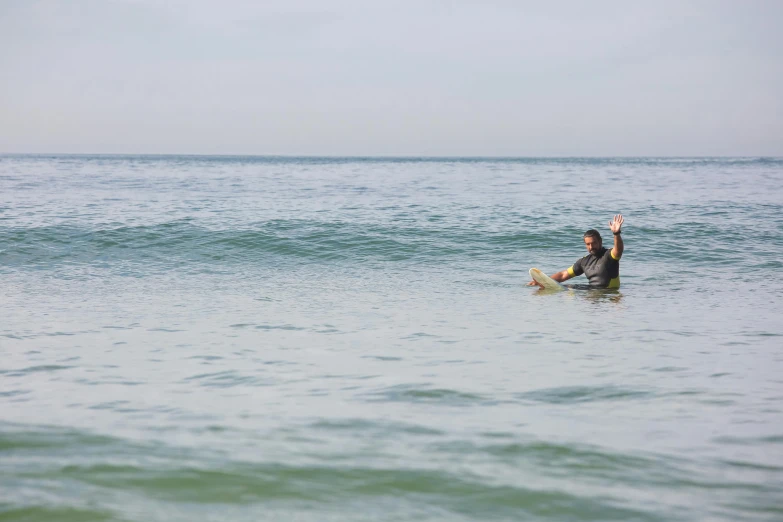 a man riding a wave on top of a surfboard, unsplash, figuration libre, waving, distant photo, sitting down, cornwall