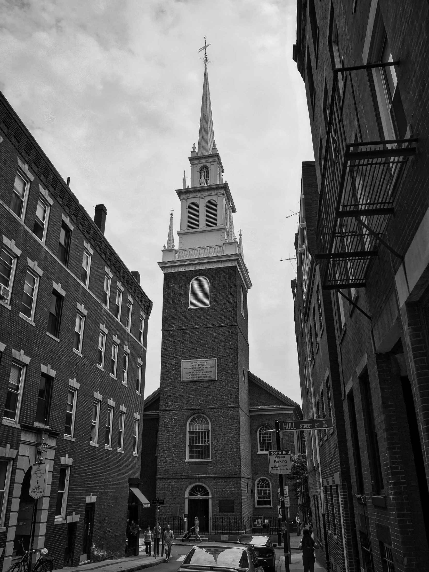 a black and white photo of a church steeple, by Adam Rex, colonial era street, by joseph binder, jordan lamarre - wan, red building