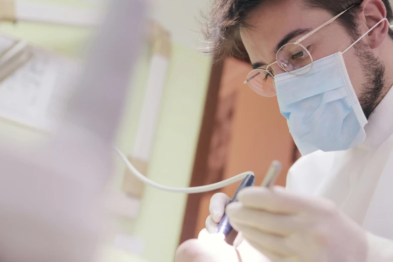 a dentist is working on a patient's teeth, pexels contest winner, background : diego fazio, student, profile image, wearing a mask