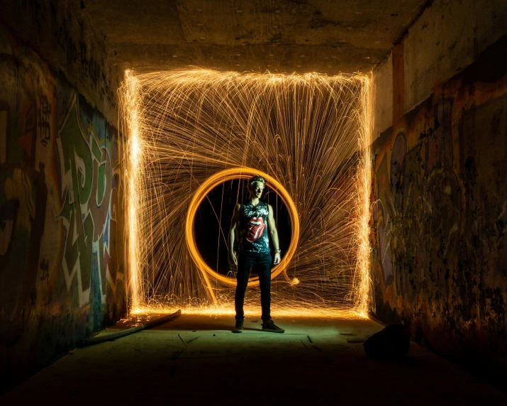 a person standing in a tunnel with a light painting, pexels contest winner, graffiti, orange halo, large electrical gold sparks, instagram post, full portrait
