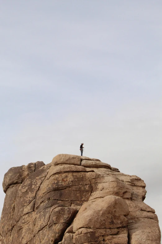 a person standing on top of a large rock, from afar