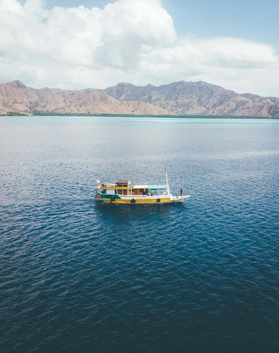 a boat floating in the middle of a large body of water, by Hannah Tompkins, pexels contest winner, sumatraism, vintage color, thumbnail, multiple stories, high angle shot