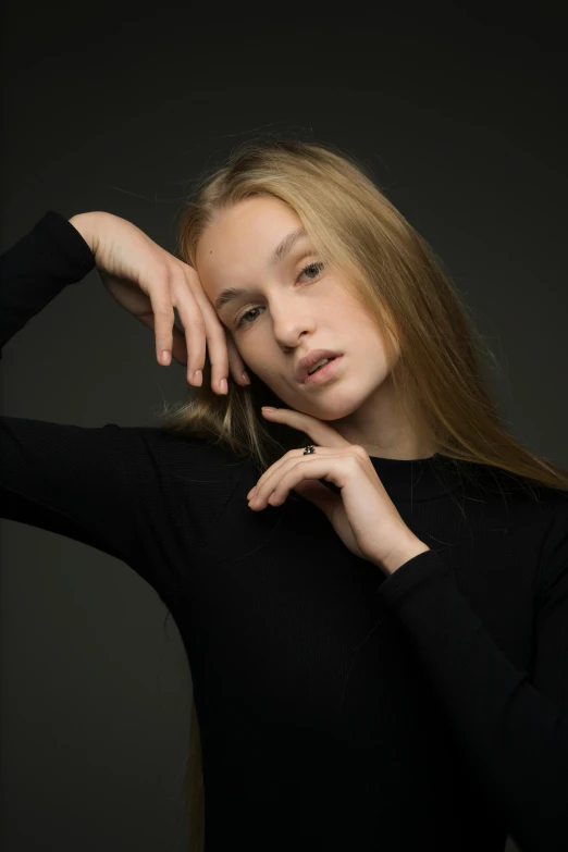 a woman in a black shirt posing for a picture, smooth pale skin, hands in her hair, she is about 1 6 years old, 5 0 0 px models