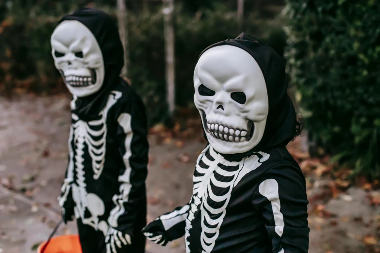 two little boys dressed up in skeleton costumes, a cartoon, by Emma Andijewska, pexels, real life size, lurking