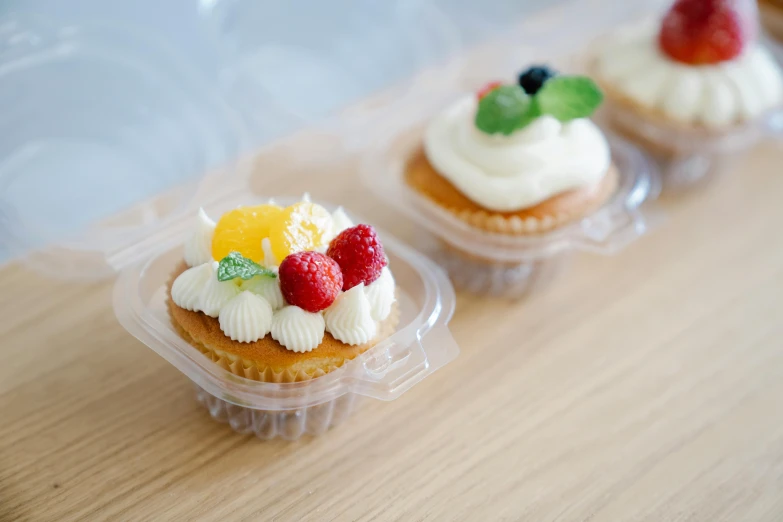 a couple of cupcakes sitting on top of a wooden table, fruit, carrying a tray, 6 pack, subtle detailing