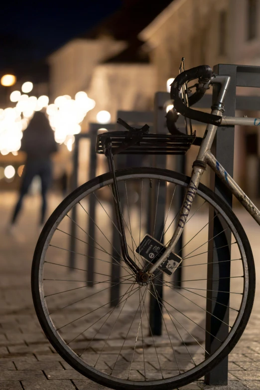 a bicycle parked on the side of a street, at night time, up close, stanchions, profile image