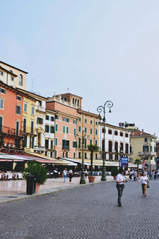 a group of people walking down a cobblestone street, inspired by Vito D'Ancona, trending on unsplash, renaissance, town square, white buildings with red roofs, seaside, “wide shot