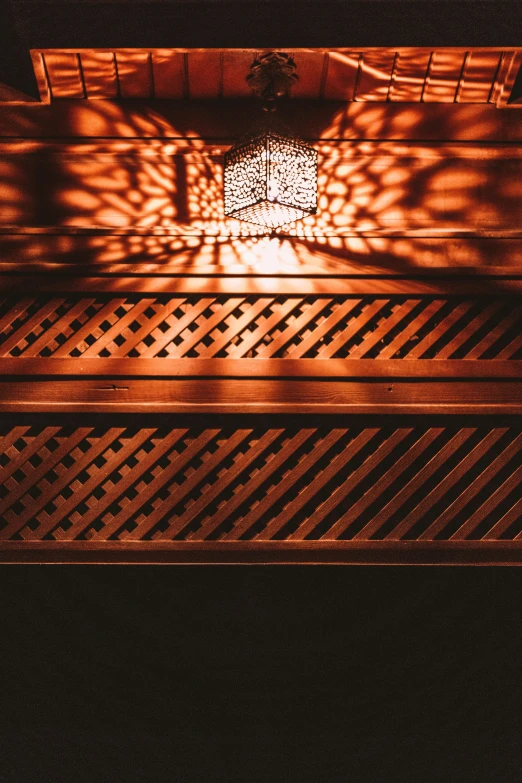 a close up of a light shining through a window, inspired by Riad Beyrouti, wooden banks, intricate lining, sauna, reddish exterior lighting