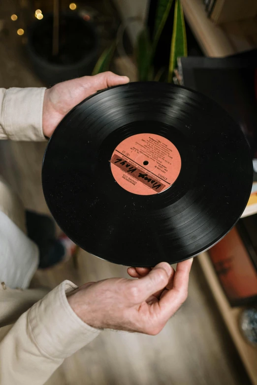 a man holding a vinyl record in his hands, an album cover, by Everett Warner, pexels contest winner, detailed product image, label, large tall, detail shot