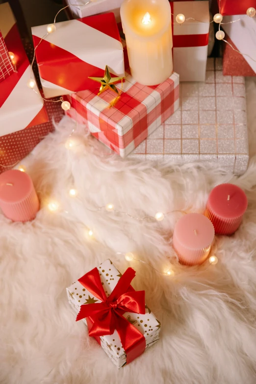 a pile of presents sitting on top of a fur covered floor, candles, pink and red color scheme, overview