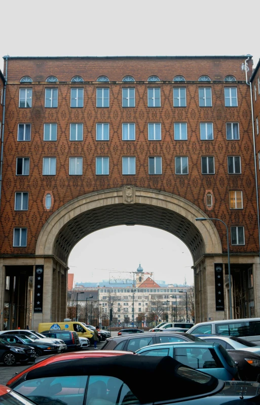 a bunch of cars that are parked in front of a building, an album cover, berlin secession, archway, view from across the street, photo taken on a nikon, military buildings