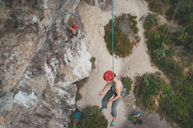 a man standing on top of a cliff while holding onto a rope, pexels contest winner, figuration libre, rock climbers climbing a rock, aerial view top down, avatar image, female ascending