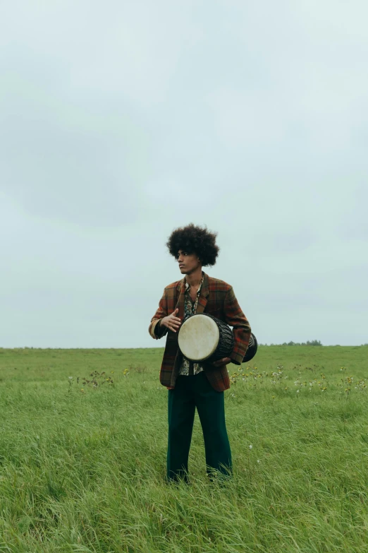 a man standing in a field holding a frisbee, an album cover, pexels contest winner, renaissance, afro hair, playing drums, movie still, cinematic outfit photo