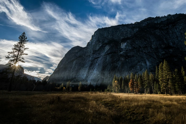 a grassy field with trees and a mountain in the background, unsplash contest winner, yosemite, rocky cliff, late afternoon, alessio albi