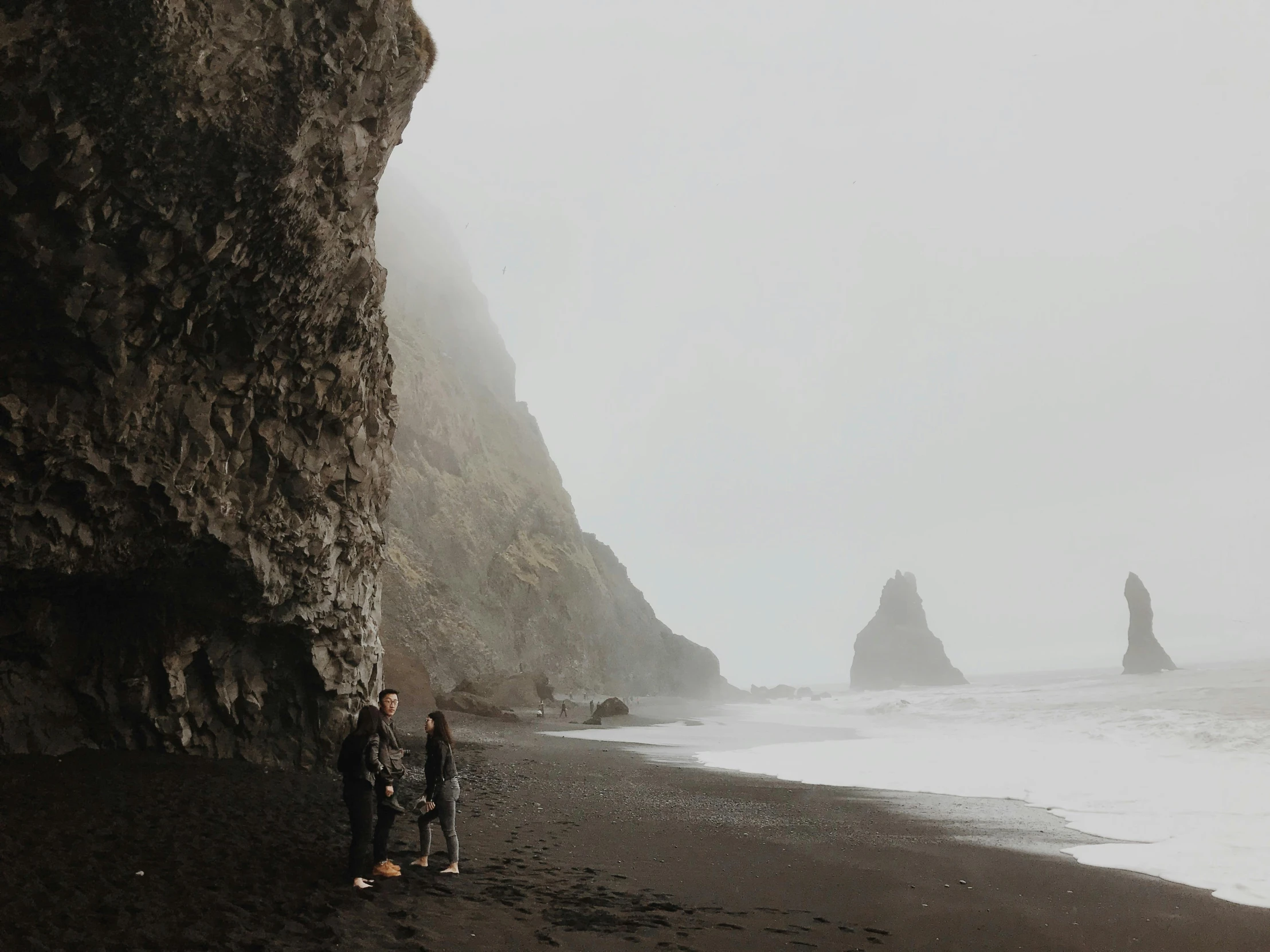 a couple of people standing on top of a beach, pexels contest winner, forest setting in iceland, grey, background image, coastal cliffs