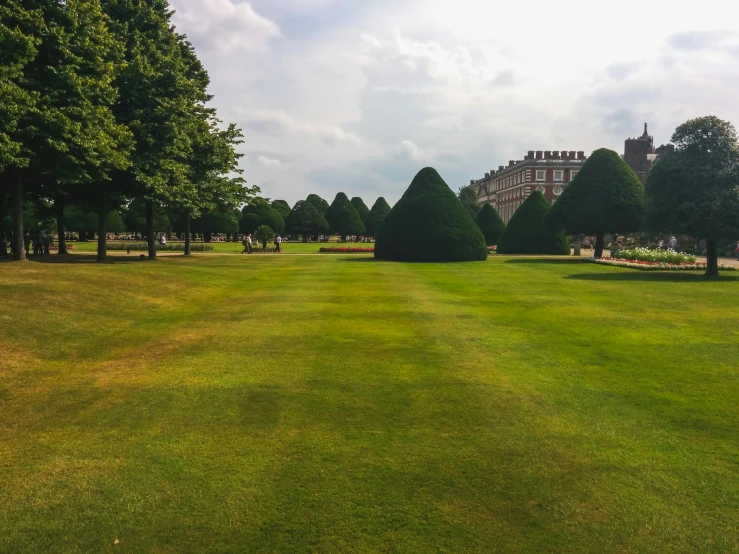 a large grassy field with trees and a building in the background, inspired by Thomas Struth, pexels contest winner, royal garden background, squares, parce sepulto, kings row in the background