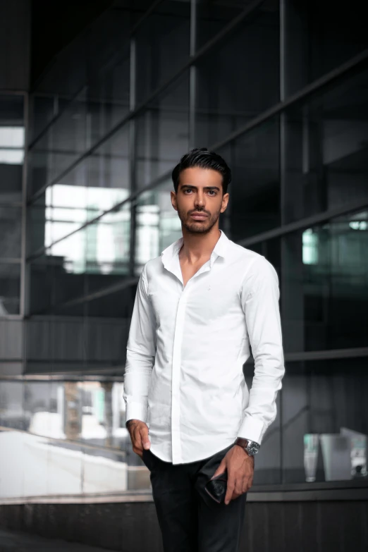 a man in a white shirt standing in front of a building, inspired by david rubín, pexels contest winner, a portrait of rahul kohli, indoor shot, black shirt, confident action pose