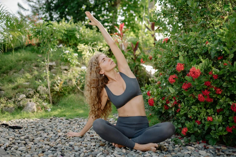 a woman sitting on the ground doing a yoga pose, by Carey Morris, pexels contest winner, curly haired, avatar image, lush surroundings, with arms up