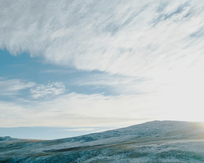 a man riding a snowboard on top of a snow covered slope, by Jessie Algie, trending on unsplash, minimalism, distant clouds, icelandic landscape, an expansive grassy plain, in muted colours