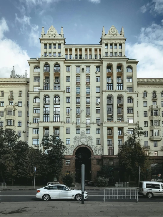 a white car parked in front of a tall building, inspired by Vassily Maximov, pexels contest winner, socialist realism, symmetrical front view, mansion, 000 — википедия, panorama view