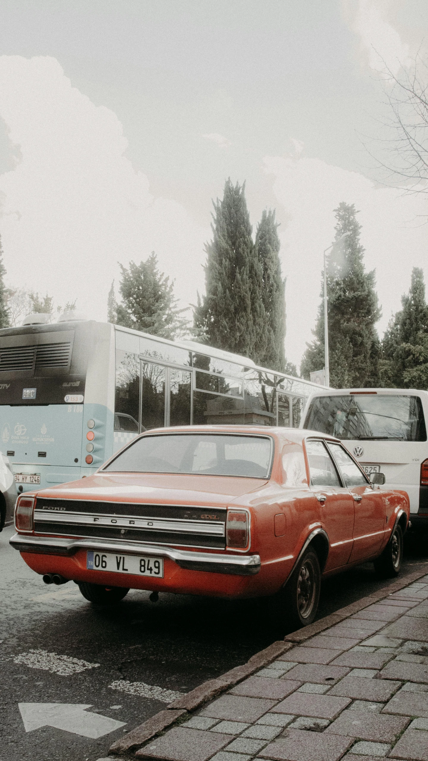 a red car is parked on the side of the road, an album cover, by Attila Meszlenyi, pexels contest winner, renaissance, retro haze, buses, analogue photo low quality, high quality photo