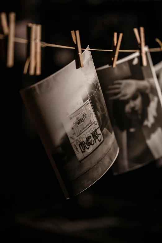 a bunch of pictures hanging on a clothes line, a black and white photo, by Lucia Peka, unsplash, close - up studio photo, medium - format print, dimly lit, vintage closeup photograph