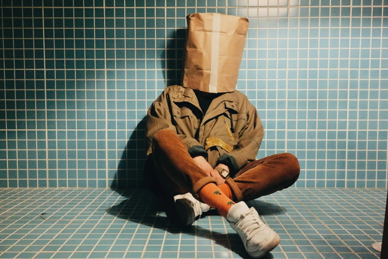 a person sitting on a tiled floor with a paper bag over their head, an album cover, unsplash, hyperrealism, buckethead, hungover, wearing only pants, toiletpaper magazine