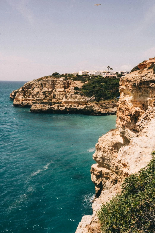 a man standing on top of a cliff next to the ocean, jerez, turquoise water, blonde, rocky cliffs