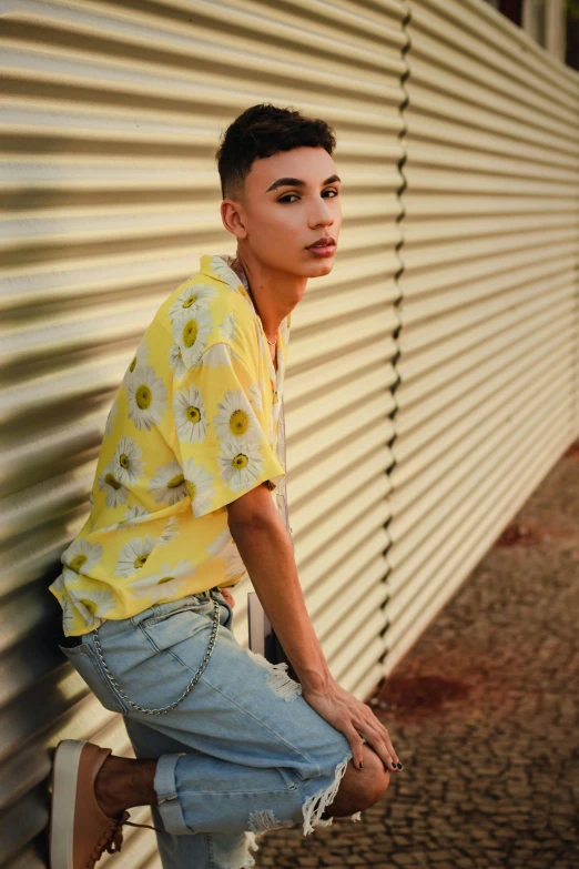 a man in a yellow shirt leaning against a wall, trending on pexels, daisy dukes, non binary model, floral, bella poarch