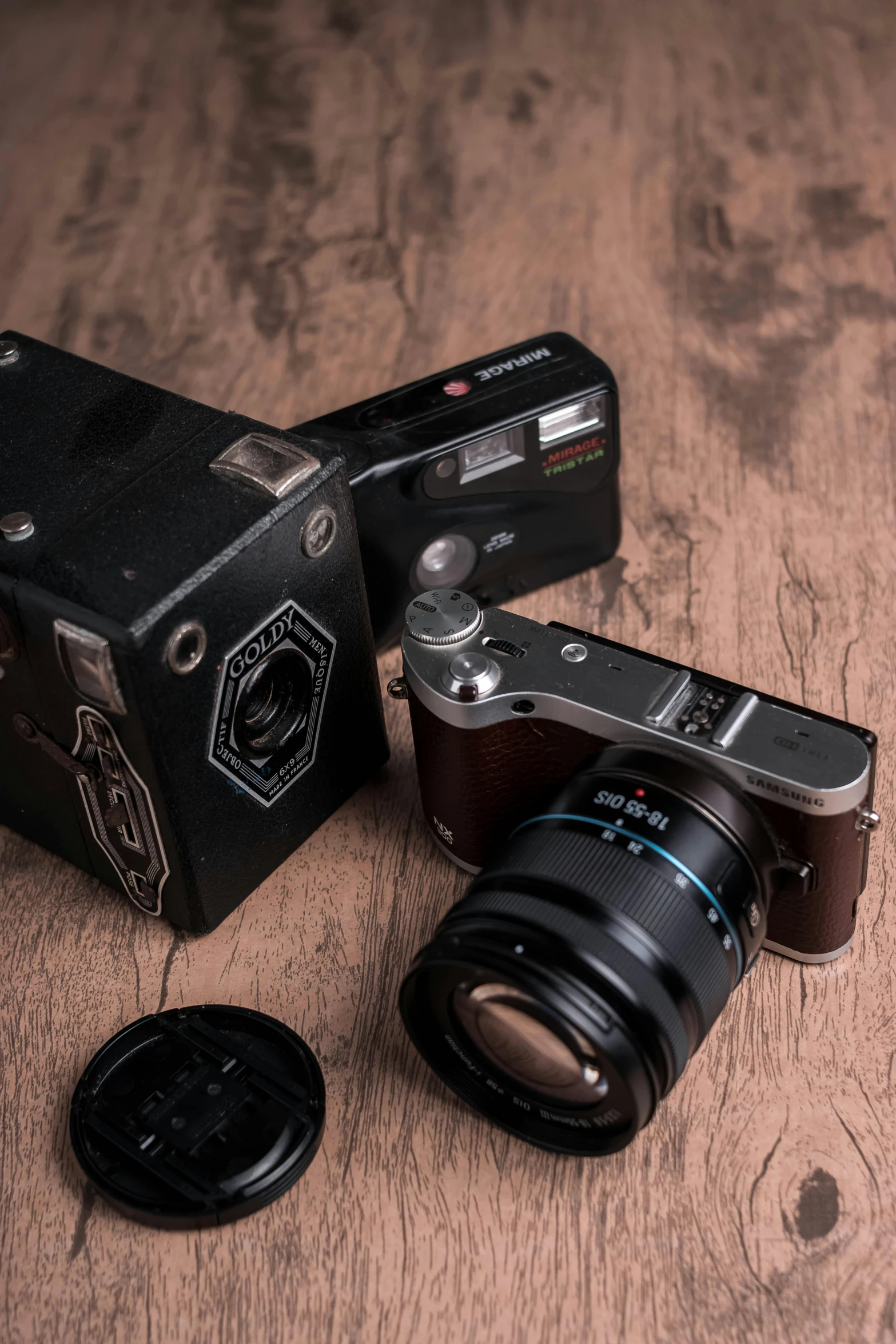 a couple of cameras sitting on top of a wooden table, by Adam Marczyński, home album pocket camera photo, miscellaneous objects, f/8.0, photo in color