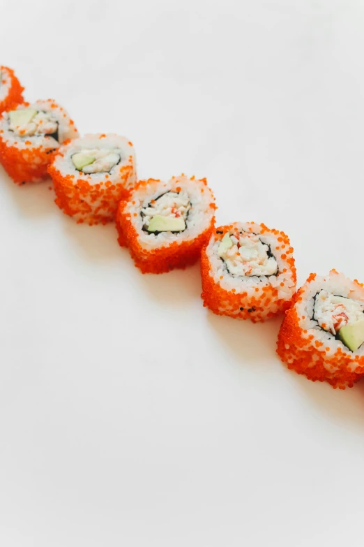 a long line of sushi rolls on a white surface, coral, sparkly, spiral, 6 pack